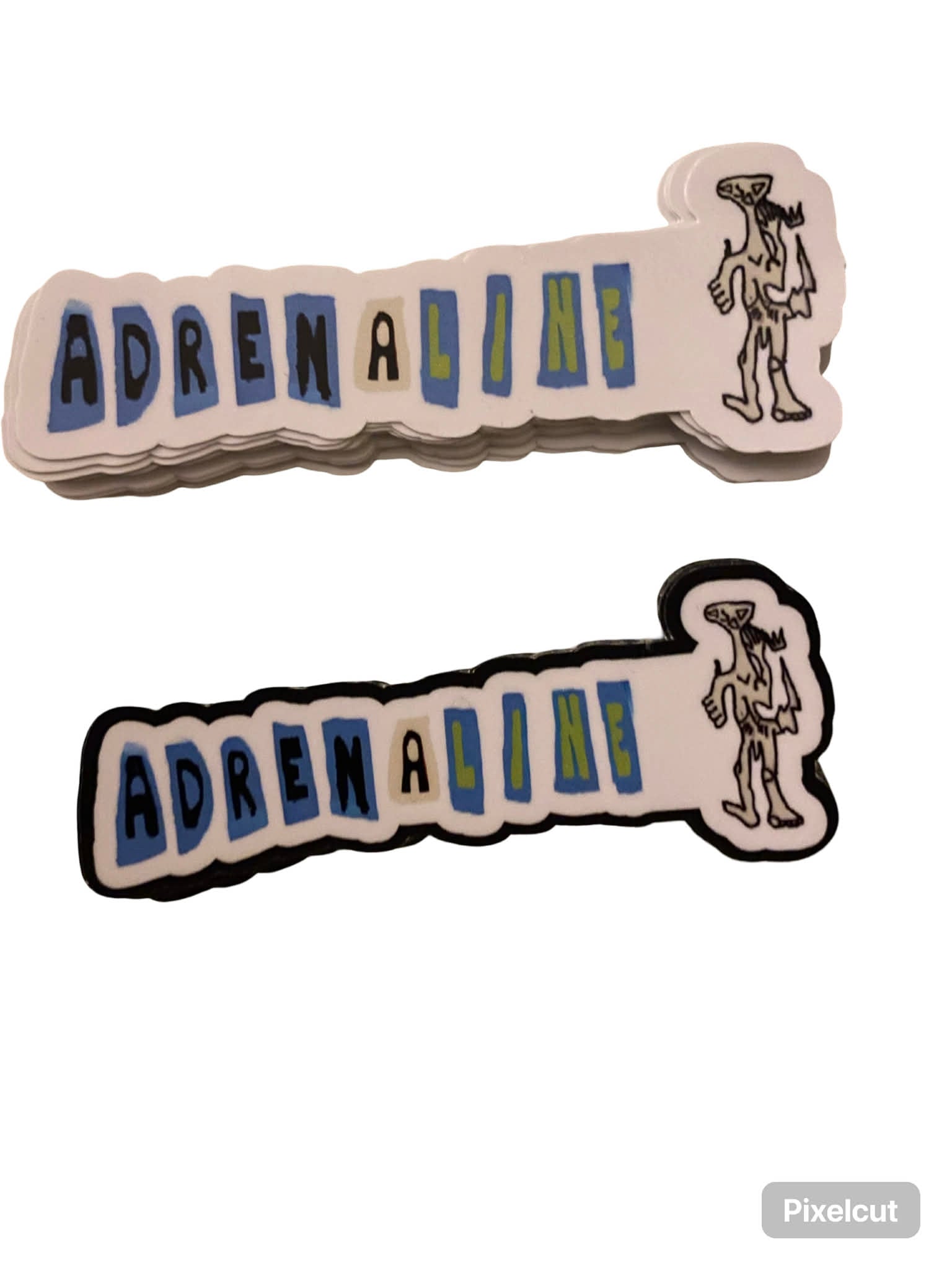 The Adrenaline alien adrenaline stickers set includes two 80mm-wide decals with "ADRENALINE" in block letters and a thin alien figure on the right—one outlined in white, one in black. Perfect for customizing any surface.